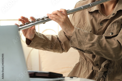 Flute classical instrument profestional player playing song. Instructor practicing bronze woodwind for orchestra as solo by online school learning through laplop. photo