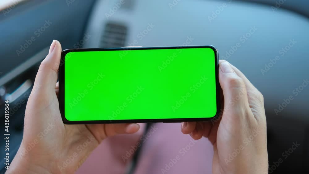 Close up of a woman's hand holding a mobile telephone with a horizontal green screen in car chroma key smartphone technology cell phone street touch message display hand