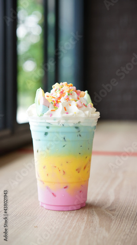 Unicorn beverage, fusion cute colorful milky menu with marchmallow. Three color in multi layers with ice in plastic cup with whipped cream.