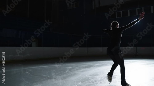  Female artistic figure skater is performing a woman's single skating choreography on ice rink before start of a competition. Slow motion 120 fps. Concept of perfection, precision, freedom, passion