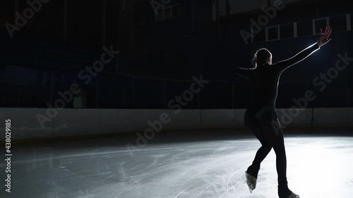  Female artistic figure skater is performing a woman's single skating choreography on ice rink before start of a competition. Slow motion 120 fps. Concept of perfection, precision, freedom, passion photo
