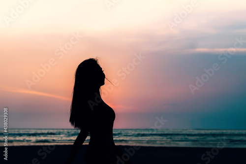 Women silhouette on beach during sunset.