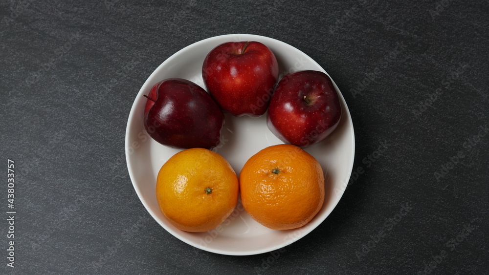 red apples and oranges in a bowl