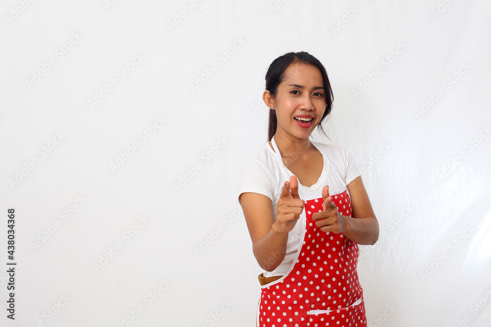 Portrait of asian woman wearing kitchen apron isolated on white background while pointing his finger into a camera Portrait of asian woman wearing kitchen apron isolated on white background while pointing his finger into a camera