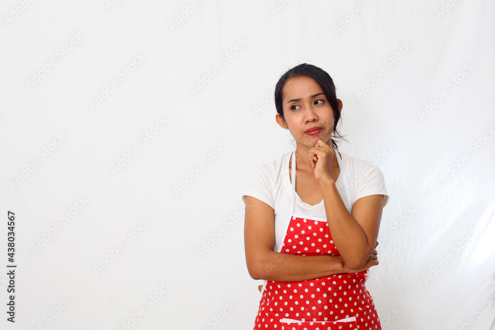 Portrait of asian woman wearing kitchen apron isolated on white background while thinking something Portrait of asian woman wearing kitchen apron isolated on white background while thinking something