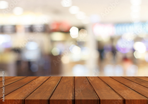 Empty brown wood table top on blur abstract background from inside shopping mall, Used for display or montage your products.