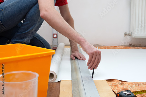 Man repair measures the length of the strip of wallpaper. renovation apartment.