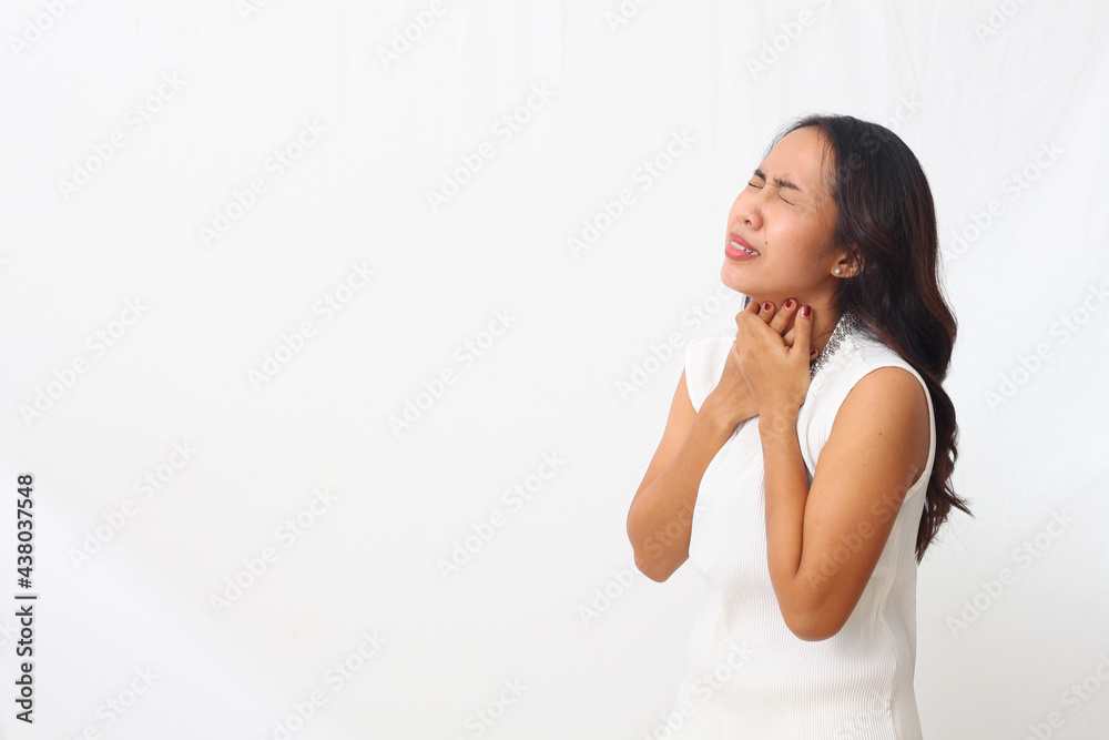 Beautiful asian girl standing while holding her neck. The concept of a sore throat. Isolated on white background with copyspace