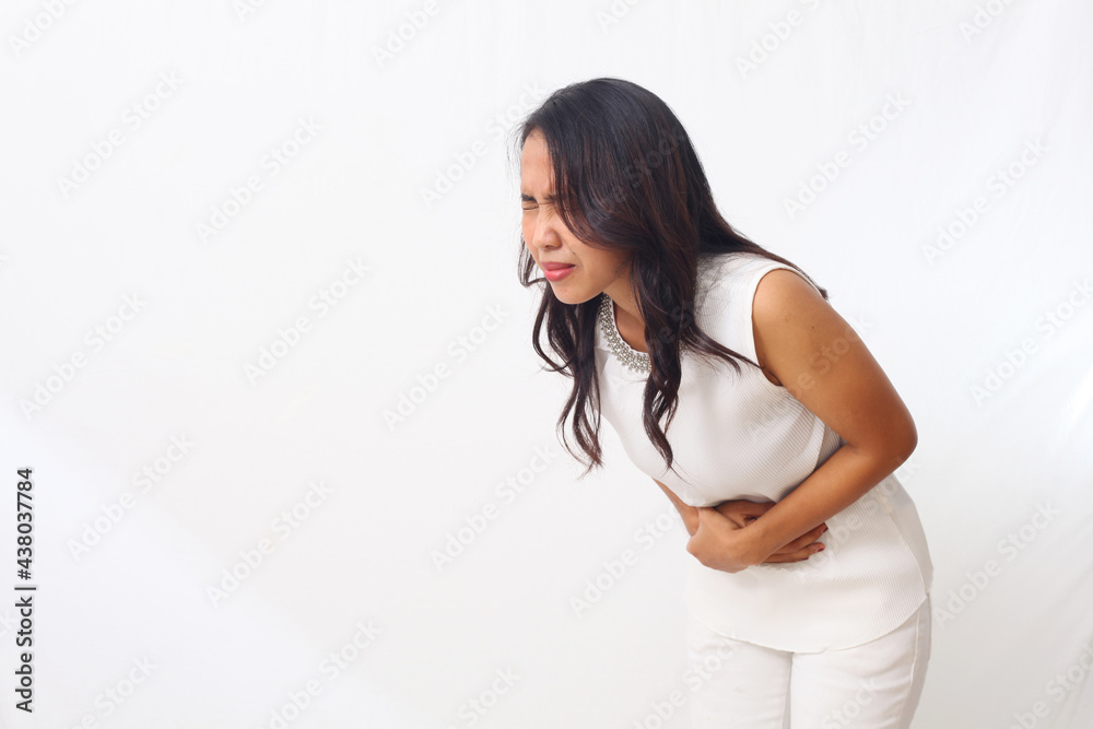 Beautiful asian girl standing while holding her stomach. healthcare concept. Isolated on white background with copyspace