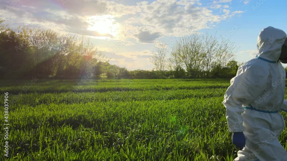 Male in protective biohazard suit walking through field, virus pandemic bio war Male in protective biohazard suit walking through field, virus pandemic bio war