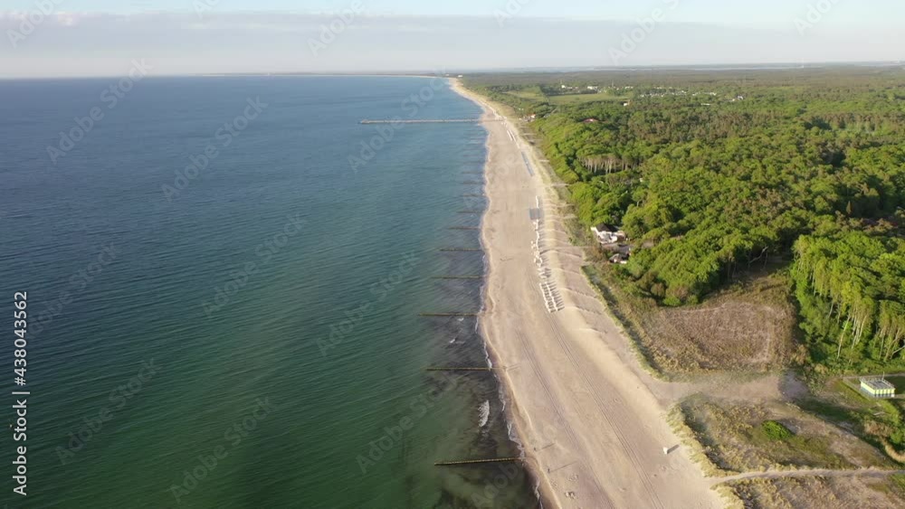 backward flight while overflying an empty sandy beach in high level with beech forest on one side and the ocean on the other side. The shore line is protected with breakwater backward flight while overflying an empty sandy beach in high level with beech forest on one side and the ocean on the other side. The shore line is protected with breakwater