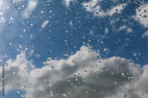 Tropfen vor Gitterstruktur mit Wolken im Hintergrund