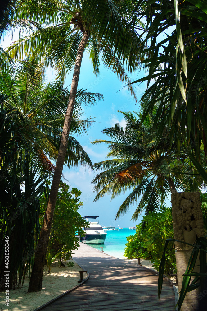 Fototapeta premium Scenic landscape of Maldives beach and pier with speed boats and yachts on the horizon. Seascape with water bungalows, beautiful turquoise sea and lagoon waters, tropical nature paradise. 