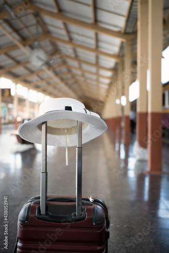 Plastic suitcase and white hat on the railroad platform. Holiday and travel concept.