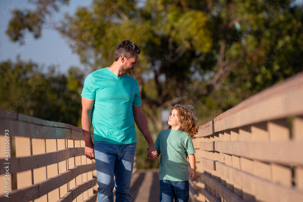 Father with son walking on wooded bridge outdoor.