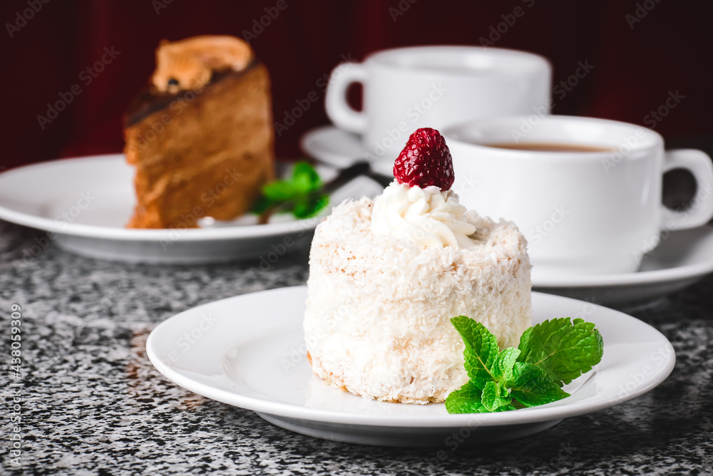 Coconut cake on a white plate with other food on the background. Coconut cake on a white plate with other food on the background.