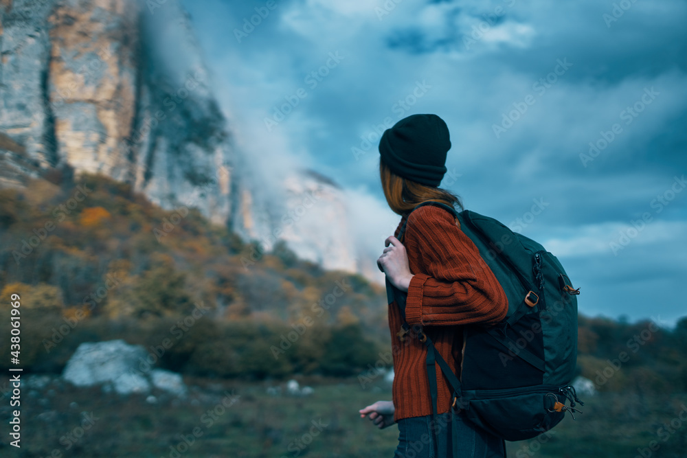 Traveler in a sweater with a backpack on her back tourism clouds sky landscape Traveler in a sweater with a backpack on her back tourism clouds sky landscape