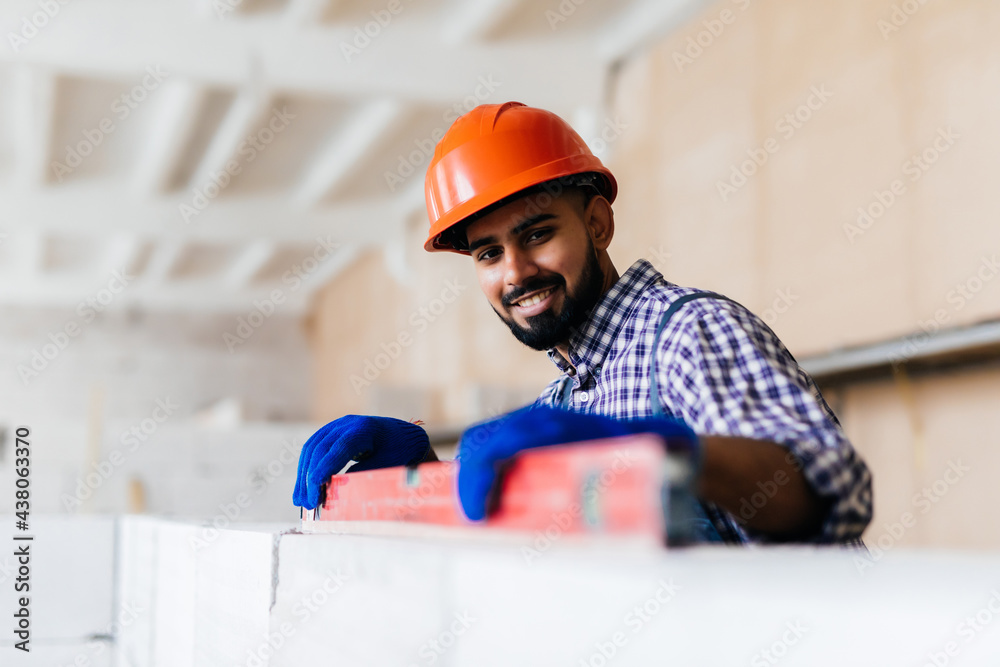 Young mason checking plumb line of house wall being made from aerated autoclaved concrete blocks Young mason checking plumb line of house wall being made from aerated autoclaved concrete blocks