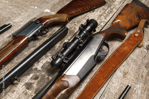 Many hunting rifles on weathered wooden surface