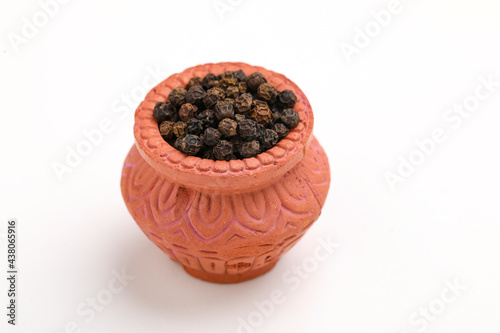 Black pepper in clay bowl.