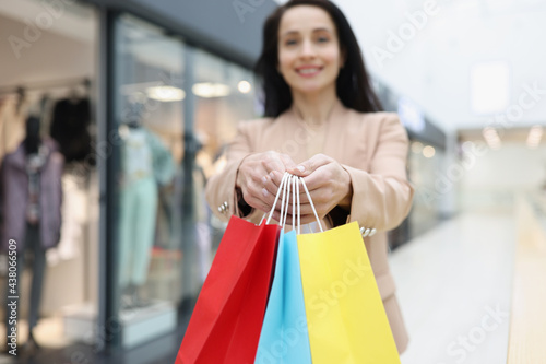 Woman holding in hands many multicolored paper bags with purchases in store closeup