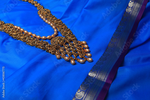 Indian traditional gold Indian wedding women's jewelry on blue saree background. Close-up. Still-life.