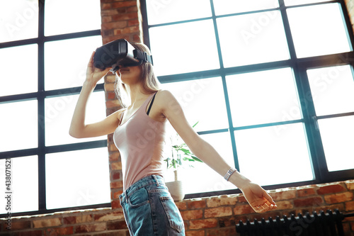 A blonde woman looks at virtual life wearing VR in the office