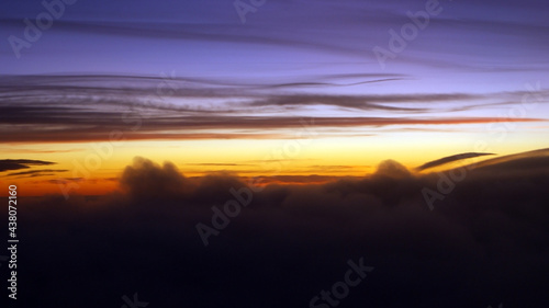 Colorful sunset seen from an airplane window. Cloud silhouette photo taken kilometers high.