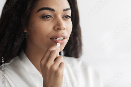 Young african american woman taking medicine, eating beauty supplement pill, closeup, free space