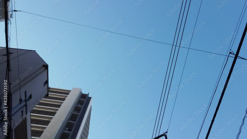 POV to the sky while walking in the local area in tokyo small area town with clear blue sky POV to the sky while walking in the local area in tokyo small area town with clear blue sky