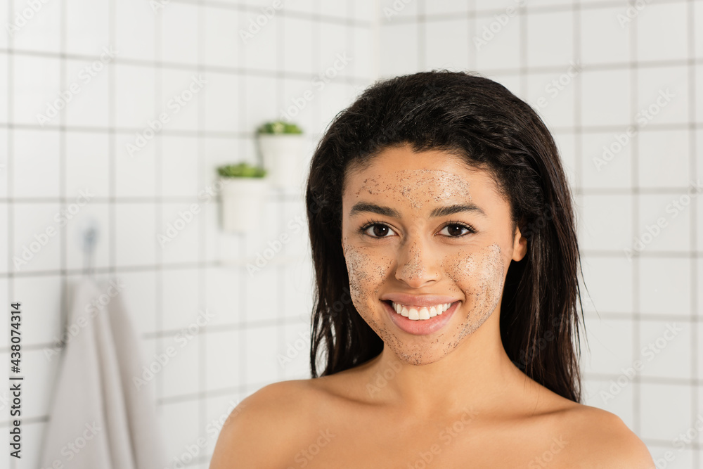 african american woman with scrub on face looking at camera in bathroom african american woman with scrub on face looking at camera in bathroom