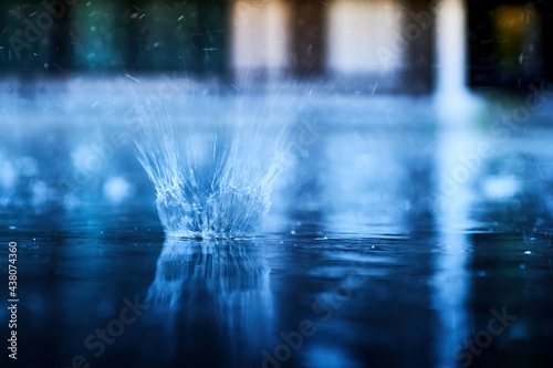 small splashing crown from rain's droplet when fall down on the floor in rainy day with blue shade color tone and golden sun light behind © photopk