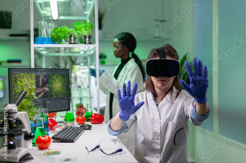 Researcher with virtual reality headset researching new genetic experiment for microbiology expertise. Medical team working in pharmaceutical laboratory analyzing dna test.