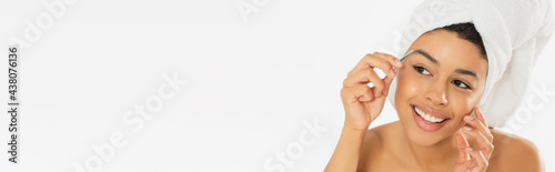 Canvas Print positive young african american woman plucking eyebrows with tweezers on white b