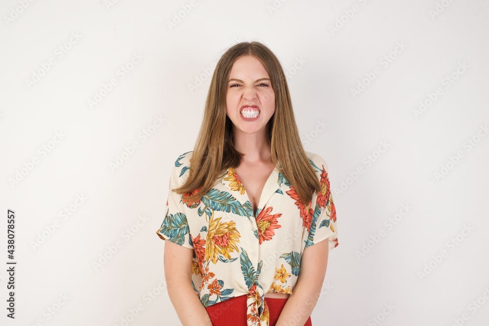 Mad crazy woman clenches teeth angrily, being annoyed with coming noise, dressed in fashionable clothes, isolated over white background. Negative feeling concept. Mad crazy woman clenches teeth angrily, being annoyed with coming noise, dressed in fashionable clothes, isolated over white background. Negative feeling concept.