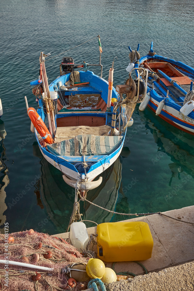 typical Mediterranean colored wooden fishing boats moored at the port of an island with clear and clean sea in Sicily in San Vito lo Capo in the Province of Trapani