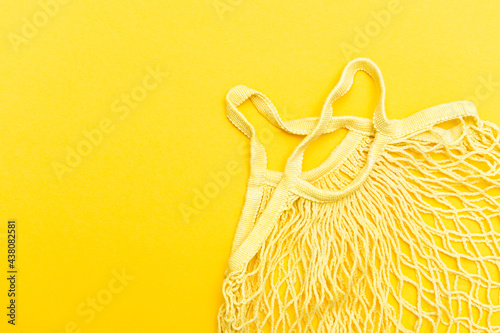 Empty mesh bag for shopping on a yellow background isolated. Zero waste shopping concept