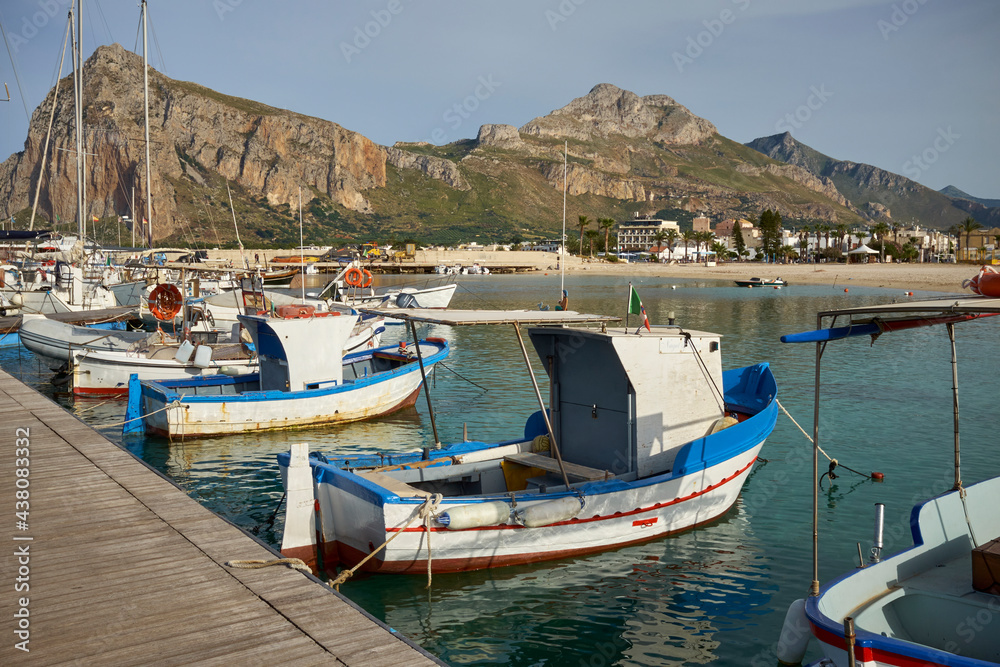 typical Mediterranean colored wooden fishing boats moored at the port of an island with clear and clean sea in Sicily in San Vito lo Capo in the Province of Trapani