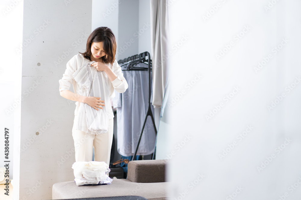 自宅で洗濯物をたたむ若い女性 自宅で洗濯物をたたむ若い女性