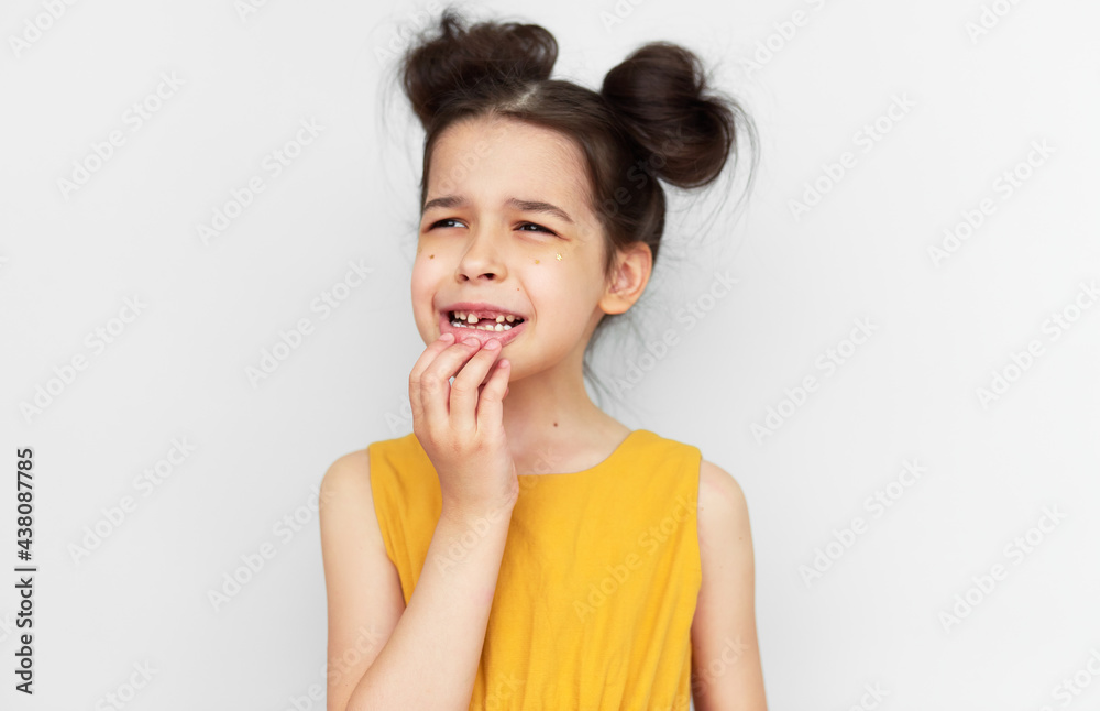 Portrait of preschool cute little girl showing empty space with growing first permanent molar, isolated on grey studio background. A child has lost the first milk tooth. Kid losing primary baby teeth. Portrait of preschool cute little girl showing empty space with growing first permanent molar, isolated on grey studio background. A child has lost the first milk tooth. Kid losing primary baby teeth.