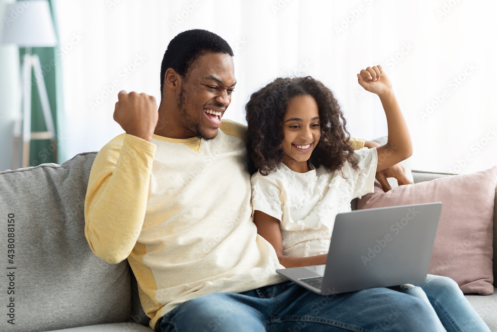 Emotional black dad and daughter using computer at home Emotional black dad and daughter using computer at home