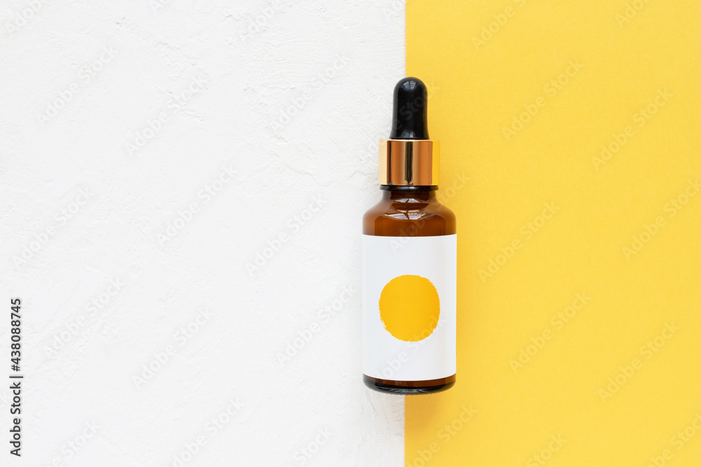 Beautiful brown glass skincare bottle on a white and yellow background, flat lay. Beautiful brown glass skincare bottle on a white and yellow background, flat lay.