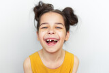 Closeup portrait of happy preschool little girl in yellow dress smiling broadly and showing empty space with growing first permanent molar isolated on grey studio background. Child missing baby tooth.