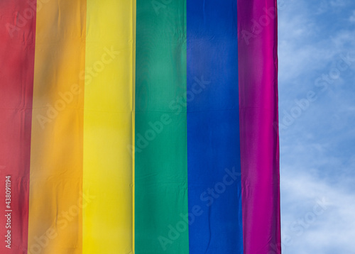 Rainbow flag in sunshine against blue sky