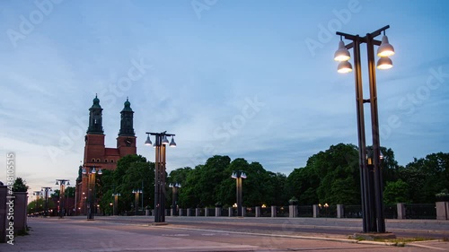 Eskilstuna, Sweden - May 31, 2021. Day to night time lapse of car light driving and long way street pole light in city on twilight sunset sky. Klosters kyrka church land mark building background photo