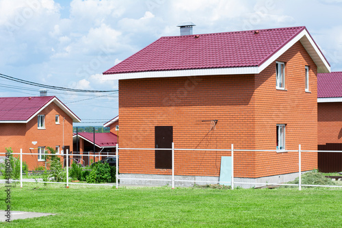 New two-story brick house, red, orange color. A house in a village near the city. Modern house. photo