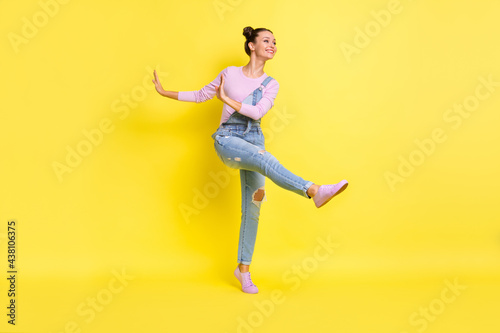 Full length photo of cute charming young woman wear denim overall dancing isolated yellow color background