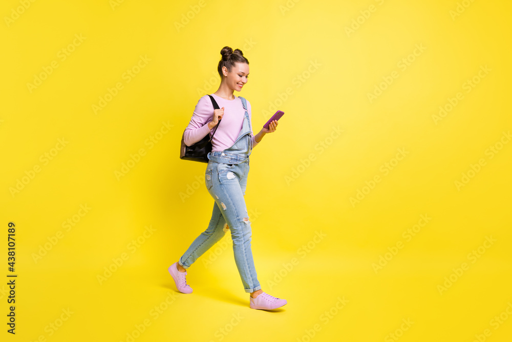 Full size profile photo of optimistic nice brunet lady go look telephone wear overall isolated on yellow background