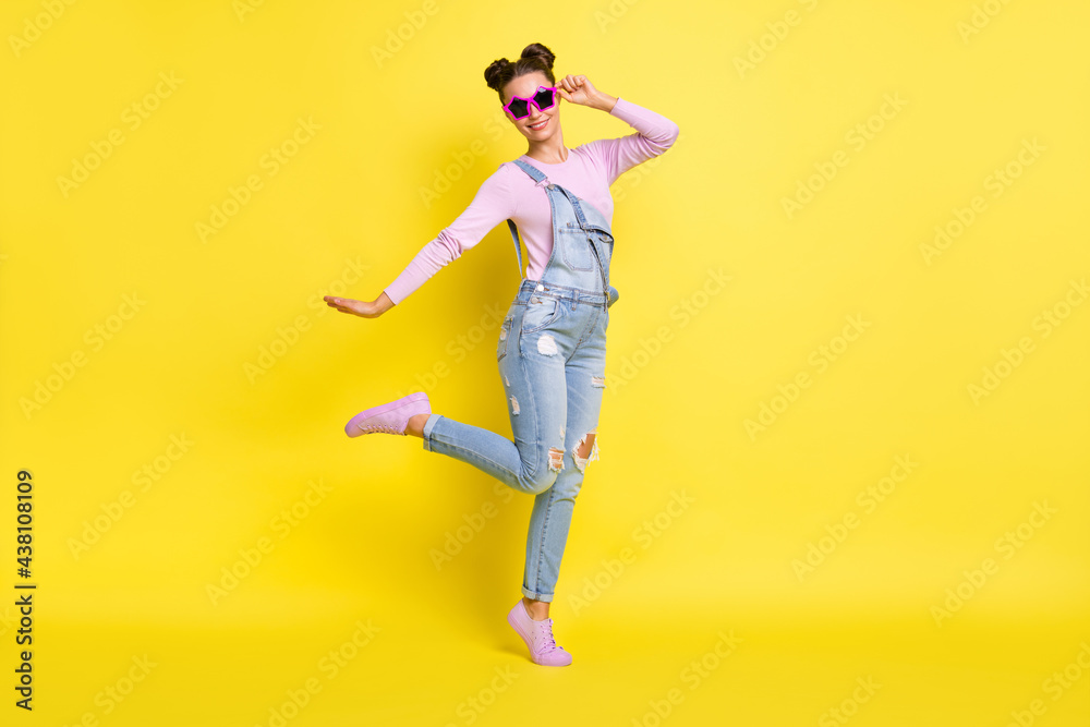 Photo of sweet cool young lady dressed jeans overall dark glasses dancing isolated yellow color background