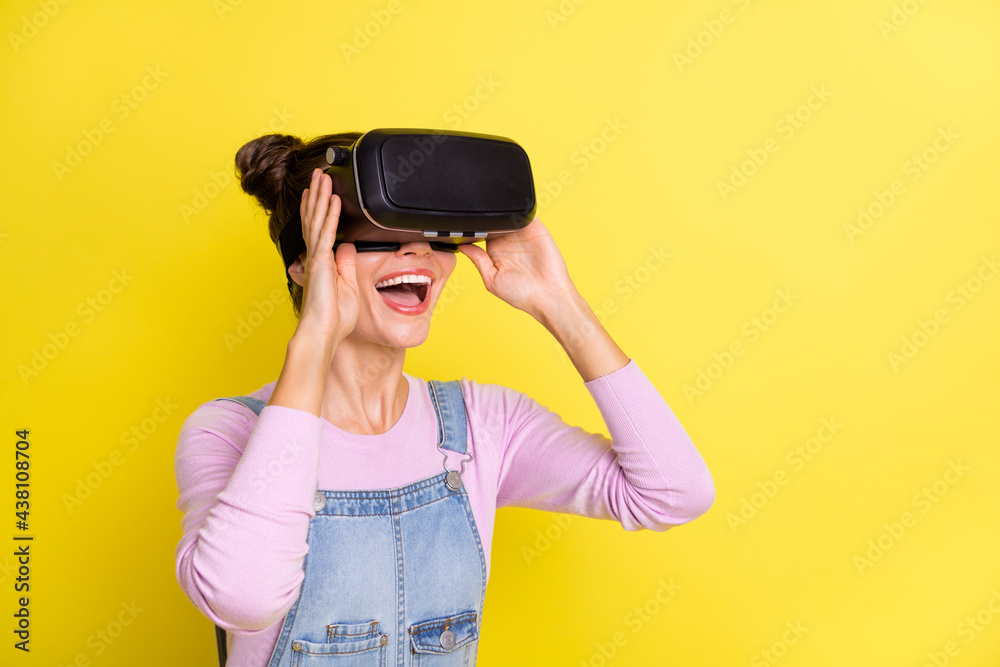 Photo of impressed funny young woman wear denim overall looking 3d glasses empty space isolated yellow color background